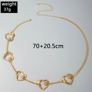 Detail of gold metal waist chain featuring five hollow heart-shaped charms for beach wear