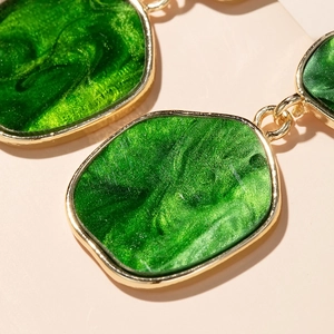 Detail of green enamel geometric earrings with vintage style gold metallic edges