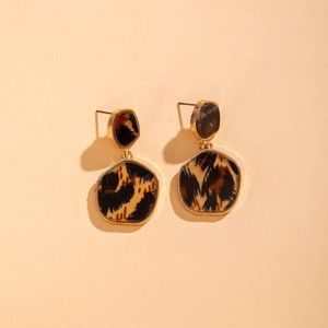Detailed view of geometric gold earrings with leopard print inlay in a vintage style