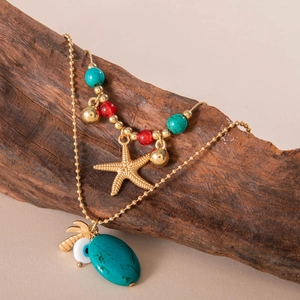 Detailansicht der mehrlagigen Goldkette mit Türkisstein, Seestern und Evil-Eye-Anhängern