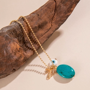 Detail der Boho-Halskette mit Palmenanhänger, Türkisstein und blauem Auge auf Holzgrund