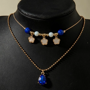 Nahaufnahme der zweilagigen Halskette mit blauen Perlen, Blumen und Kristallanhänger