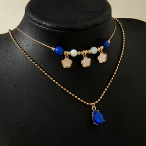 Detail einer böhmischen Doppelschicht-Halskette mit blauem Edelstein und Blumenanhängern