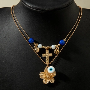 Nahaufnahme der goldenen Doppelkette mit Kreuz, Blumenanhänger und Evil-Eye-Perlen