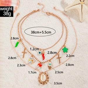 Detailed view of bohemian layered necklace set with shell, evil eye and chili charms