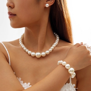 Détails d'une parure en perles blanches avec collier, bracelet et boucles d'oreilles