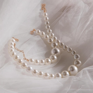 Parure de bijoux élégante avec perles dégradées et fermoir doré sur maille blanche