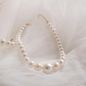 Collier élégant en perles dégradées avec chaîne dorée réglable sur tissu blanc doux