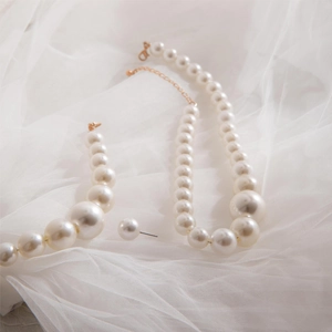 Parure de collier et boucles d'oreilles en perles avec design dégradé sur tissu blanc