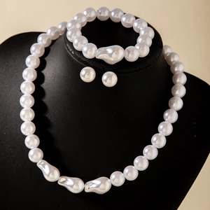 Ensemble détaillé de collier, bracelet et boucles d'oreilles en perles blanches sur socle