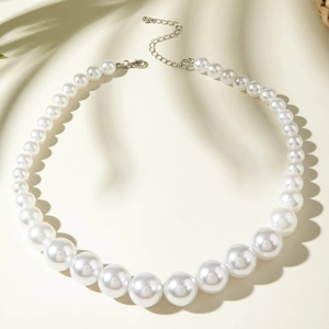 Détail du fermoir argenté et collier de perles dégradées sur fond de tissu doux