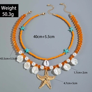 Detailed view of bohemian layered necklace with golden starfish and pearl charms