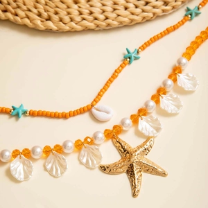 Detail of bohemian necklace with orange beads, white faux pearls and gold starfish pendant