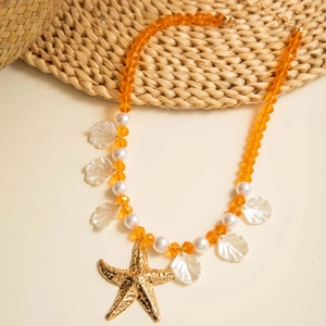 Detail of beach necklace with orange beads, starfish pendant and shell charms