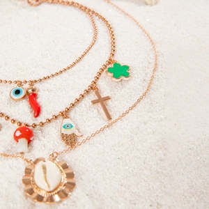 Bohemian multilayer gold bead necklace with shell, chili, and evil eye charms on sand