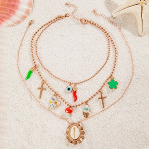Bohemian multi-layer gold necklace with shell and evil eye pendants on beach sand