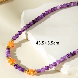 Detail of beaded necklace featuring purple marble beads and orange starfish charms