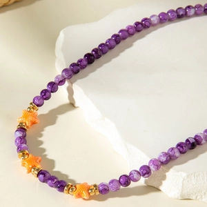 Detail of beaded shell necklace with purple marbled beads and orange starfish pendant