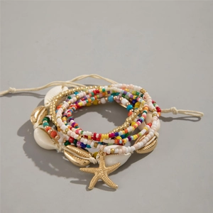 Macro shot of bohemian seashell and starfish layered beaded bracelets with beach vibes