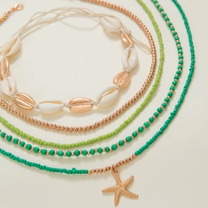 Detail view of Bohemian seashell and starfish charm necklace set with green beads