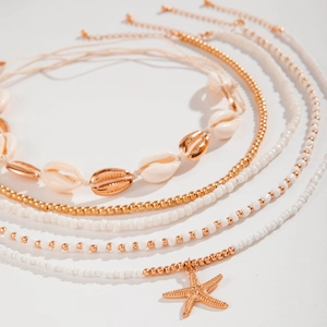 Detail of layered bohemian beach anklet with natural shell charms and golden starfish charm