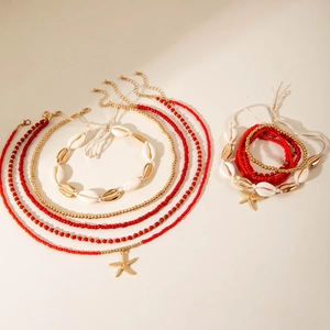 Detail of bohemian starfish shell necklaces and red beaded bracelets on white background