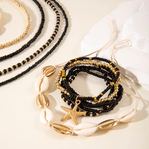 Detail of bohemian shell and starfish beaded jewelry set on white display stands