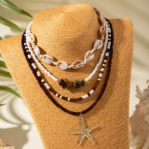 Detail of four-layer bohemian beach necklace featuring white shells and a golden starfish