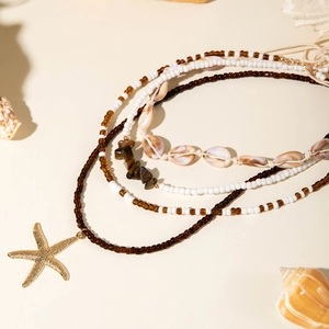 Detail of bohemian layered necklace with natural shell beads and gold starfish pendant