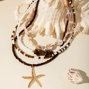 Detail of layered bohemian necklace with cowrie shells, beads and golden starfish pendant
