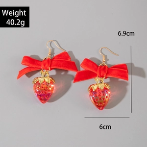 Vue détaillée de boucles d'oreilles nœud en velours rouge avec fraises 3D et crochets dorés