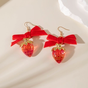 Détail des boucles d'oreilles fraises avec nœuds en velours et pendentifs résine