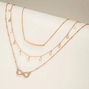 Detailed view of layered rose gold necklaces with star charms and infinity pendant