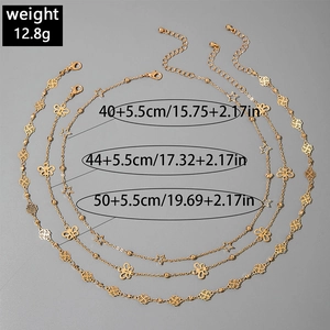 Gold layering necklace set with star, butterfly, and rose charms on a dark backdrop