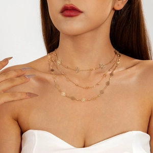 Close-up of a triple-layered gold necklace with butterfly, star, and rose pendants