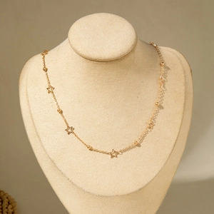 Close-up of golden necklace featuring delicate star pendants and small metal beads