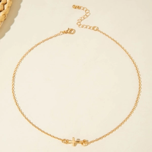 Close-up of gold chain necklace with horizontal cross pendant and lobster clasp detail