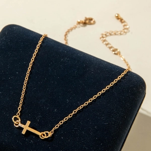 Close-up of golden cross necklace on blue velvet box featuring a thin adjustable chain