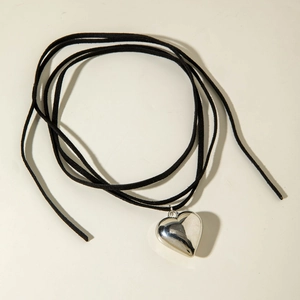 Detalle macro del colgante de corazón de plata pulida con collar de cordón de terciopelo