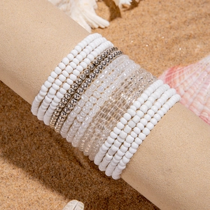 Detail of multi-layer bohemian bead bracelets with shell and beach vacation scenery