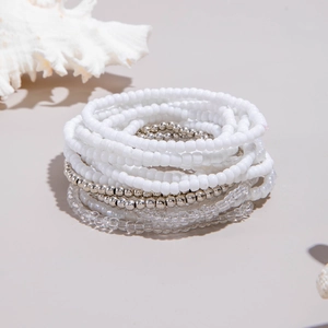 Detail of stacked bohemian seed bead bracelets in white, silver, and transparent tones