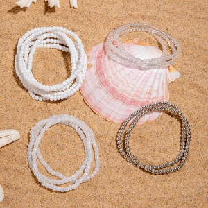 Detail of four-piece bohemian beaded bracelet set with sea shells on beach sand