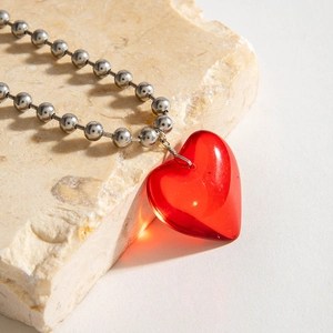 Primer plano de un colgante de corazón rojo translúcido en cadena de bolas de plata