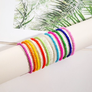 Detail of 12 multi-color bohemian seed bead bracelets stacked on a white jewelry display