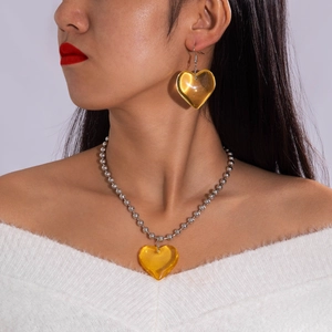 Detalle de collar de terciopelo con colgante de corazón ámbar y pendientes a juego