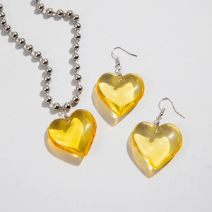Detalle de conjunto de joyas corazón de resina amarilla con cadena de bolas de plata