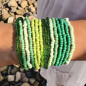 Detail of bohemian green and yellow seed bead multilayer stackable stretch bracelets