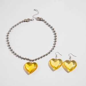 Detalle del conjunto de collar con colgante de corazón de resina amarilla y aros