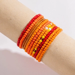 Detail of multi-layered elastic beaded bracelets in vibrant red, orange and yellow tones