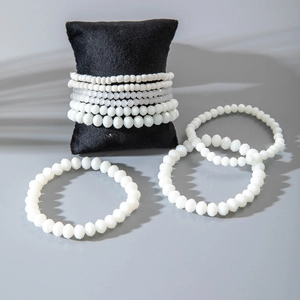 Detail of white faceted seed bead bracelets stacked on a black velvet display pad